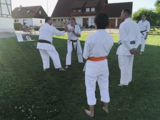 Drei Karateka beobachten, wie zwei Karateka eine Bunkai demonstrieren.